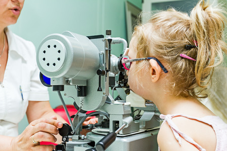 Girl undergoing eye is at examination in clinic with special equipment.の写真素材