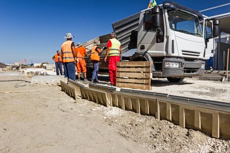 Workers are unloading material form truck for water during a heavy rain, runoff flows.