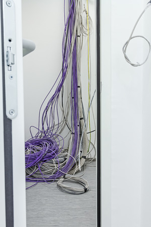 A bundle of communication cables are hanging from the ceiling in room.