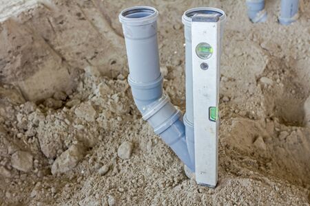 Placing set of new plastic sewer pipes into the ground assembled and lined up on building site.