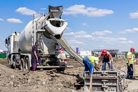Workers at building site are pouring concrete in reinforced mold.のeditorial素材