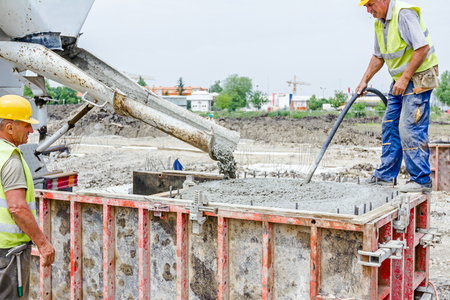 Zrenjanin, Vojvodina, Serbia - May 21, 2015: Workers at building site are pouring concrete in mold from mixer truck.のeditorial素材