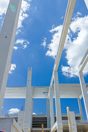Perspective view of concrete pillars, edifice in progress of growing into tall building with cloudy sky in background.の写真素材