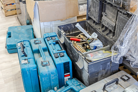 Variety of carpentry tools in tool box with open drawer on wooden floor.