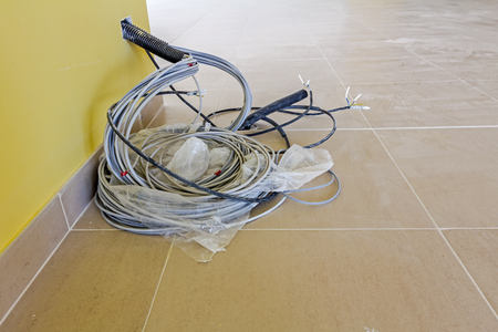 Bunch of various electric cables in corrugated pipe is coming out from the yellow wall, ready to be connected into power unit.の写真素材