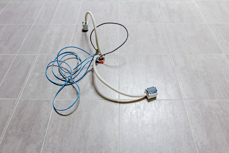 Various cables in corrugated pipe is coming out from the tiled floor, ready to be connected into...