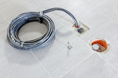 Wrapped cable in corrugated pipe is coming out from the tiled floor, ready to be connected into power unit.の写真素材