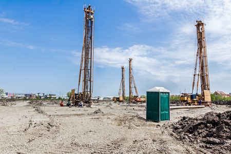 Transportable modern designed public street toilet is placed at building site, outdoor privacy. Pile...