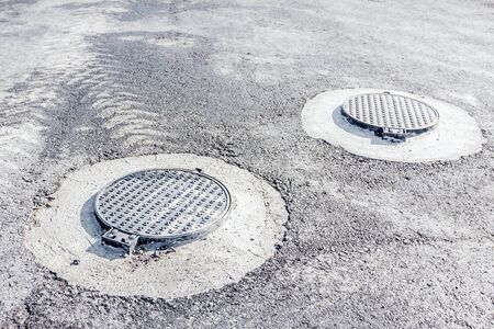 View on assembled new manhole with a metal cover, asphalt is all around.の写真素材