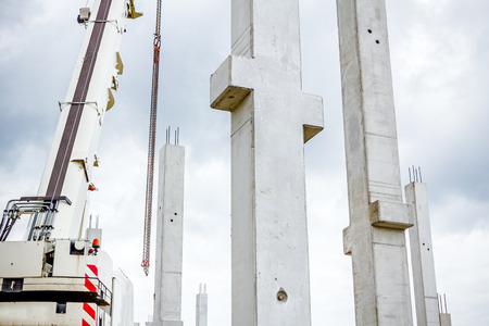 Mobile crane is operating to assembly concrete joist on new edifice.の写真素材