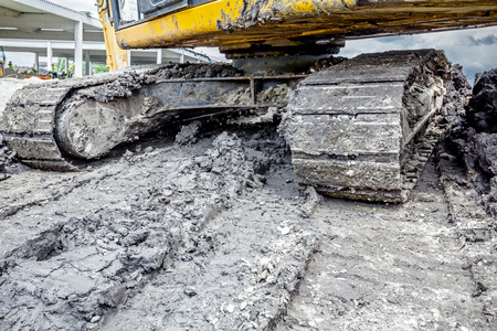 Close up view on dirty crawler during moving through mud on construction site.