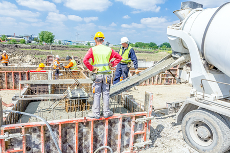 Zrenjanin, Vojvodina, Serbia - May 29, 2015: Workers at building site are pouring concrete in mold from mixer truck.のeditorial素材