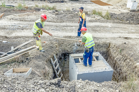 Zrenjanin, Vojvodina, Serbia - June 29, 2015: Construction workers are preparing wooden mold for concrete pouring slab on utility hole.のeditorial素材