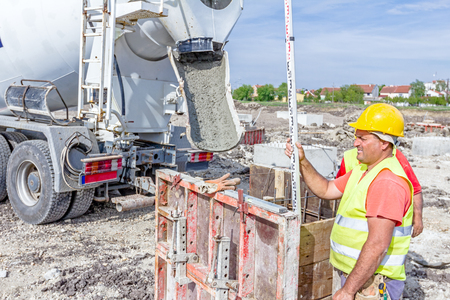 Zrenjanin, Vojvodina, Serbia - April 30, 2015: Construction worker is holding leveling rod to help surveyor, geodesist to measure position, depth.のeditorial素材