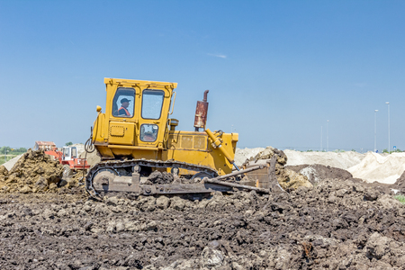 View on heavy bulldozer while he moving, leveling ground at construction site.の写真素材