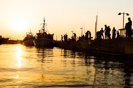 Silhouettes of fishers until they are fishing on the dock at sunset.の写真素材