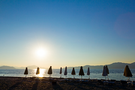 Public beach at the end of day with packed umbrellas and loungers next to the coastline.の写真素材
