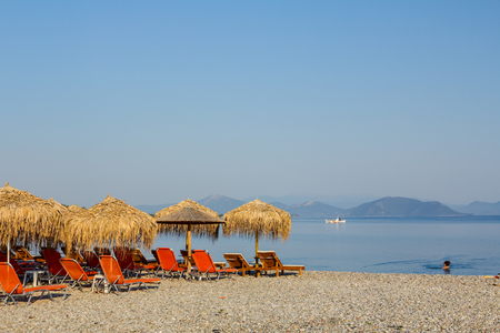 Sunshades made of straw, umbrellas and plastic deckchairs for a perfect holiday.の写真素材