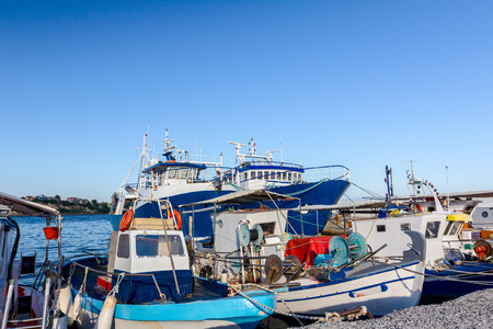 Docked colorful boats with fishing equipment are tied with ropes to the moor at the local port.の写真素材