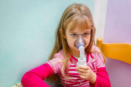 Child with asthmatic problems is take inhalation with mask on her face.の写真素材