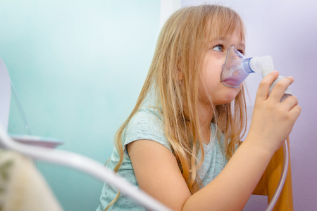 Child with asthmatic problems is take inhalation with mask on her face.