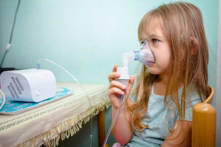 Child with asthmatic problems is take inhalation with mask on her face.の写真素材