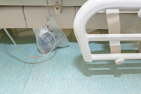Drainage bag hang on patient's bed with some blood.の写真素材