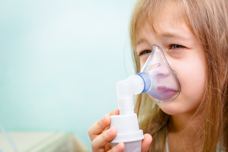 Child with asthmatic problems is take inhalation with mask on her face.の写真素材