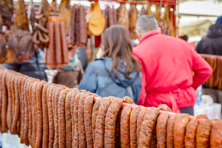 Bunch of lined cured sausages hang for sale at outdoor flea market.の写真素材