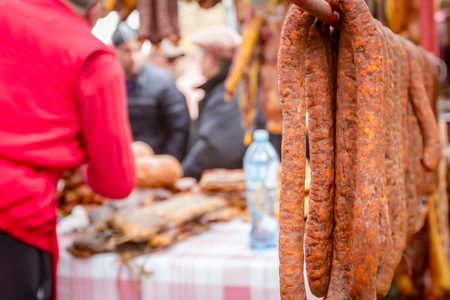 Bunch of lined cured sausages hang for sale at outdoor flea market.の写真素材