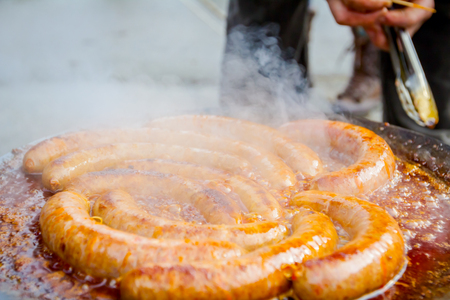 Traditional homemade pork sausages are simmering on barbecue grill, metal griddle.の写真素材