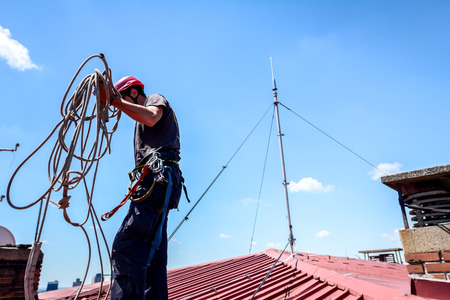 Industrial climber, alpinist, is adjusting climbing gear, arrange safety ropes.の写真素材