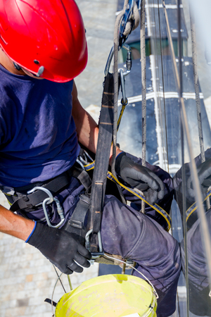 Industrial climber, alpinist, is adjusting climbing gear, preparing safety ropes.の写真素材