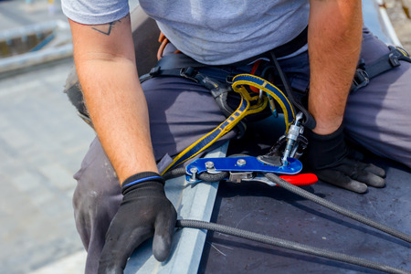Industrial climber, alpinist, is passes over roof edge. He is climb down to wash building.の写真素材