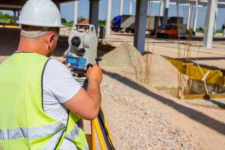 Surveyor engineer is measuring level on construction site. Surveyors ensure precise measurements before undertaking large construction projects.の写真素材