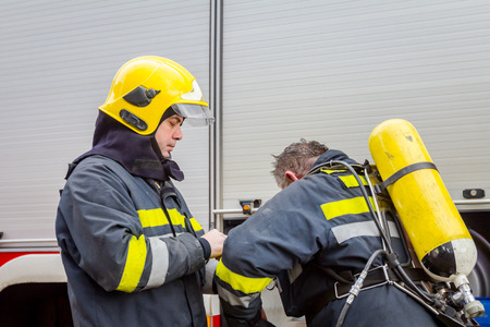 Zrenjanin, Vojvodina, Serbia - March 27, 2018: Firefighter is helping fellow to assembly his gear, keep balance and direction, checking equipment.のeditorial素材