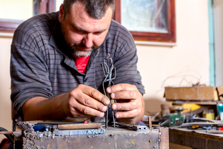 Sculptor is giving stance, attitude to his figures made of metal wire in his workshop.の写真素材