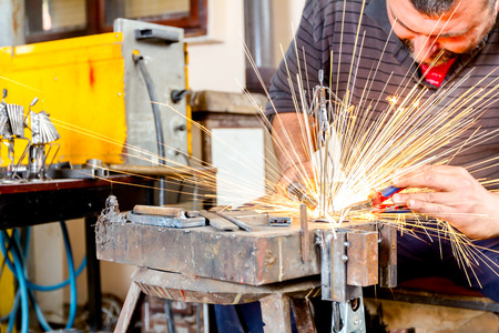 Sculptor is using arc welding to assembly metal sculpture without proper protection, barehanded.
