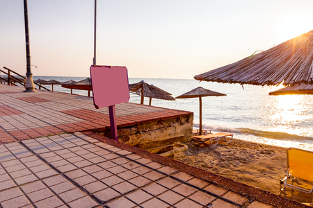 Information banner, colored wooden board is standing in front of public beach, morning time, dawn.の写真素材