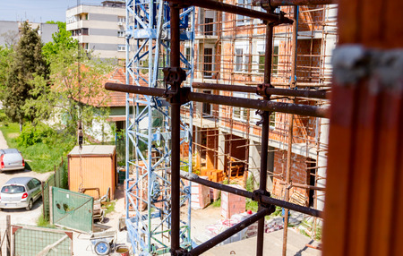 Scaffold is placed against edifice, building under construction.