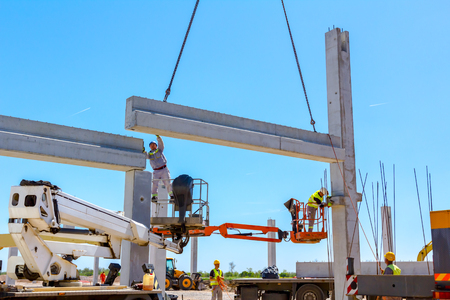 Workers are helping mobile crane to manage concrete joist for assembly huge construction.の写真素材