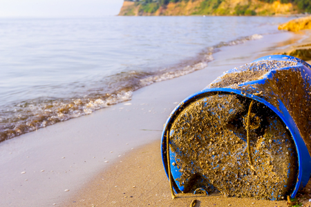 Used blue plastic drums for storing water and other liquids is washed up by the sea on sandy beach, waste.の写真素材