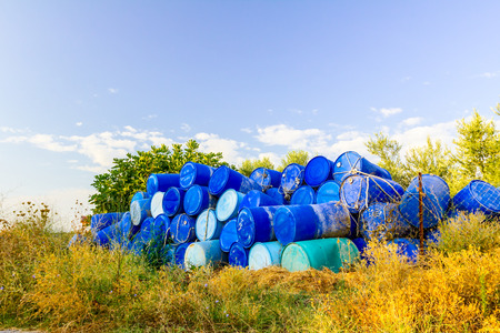 Stockpile of used blue plastic drums for storing water and other liquids.