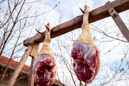 Raw pork hams are hanging on the wooden beam.の写真素材