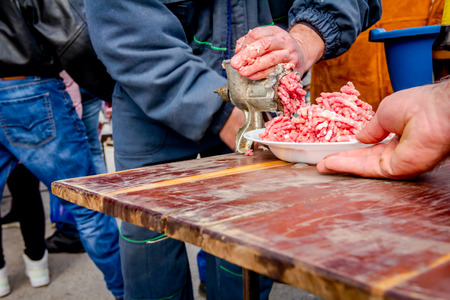 Man is working on meat grinder machine, forcemeat process for making sausages.