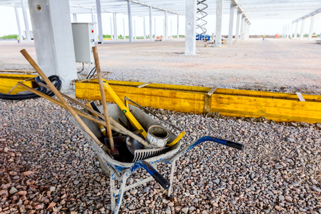 View on wheelbarrow with used equipment for earthworks at construction site.の写真素材
