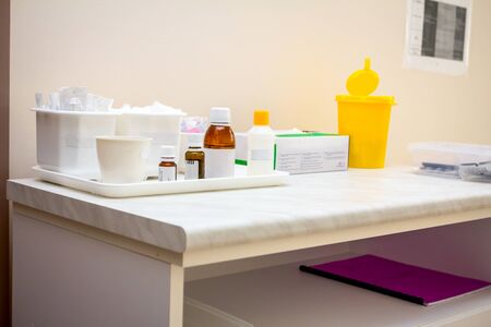 Doctor's table is covered with patient's book and various medical equipment.