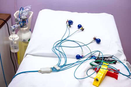 ECG or EKG electrodes for electrocardiogram records patient heartbeats on bed in hospital.