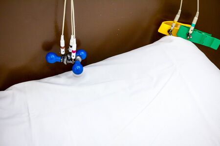 ECG or EKG electrodes for electrocardiogram records patient heartbeats on bed in hospital.