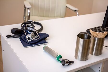 Doctor's table with medical equipment for examining the blood pressure and stethoscope.